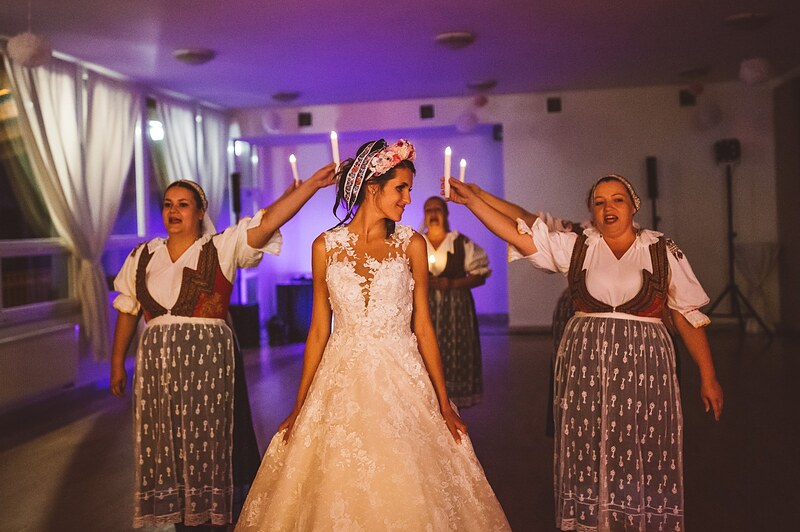 čepčenie, ženy v krojoch nasadzujú neveste čepiec, fialové nasvietenie sály. Bašta Pajštún, Borinka.