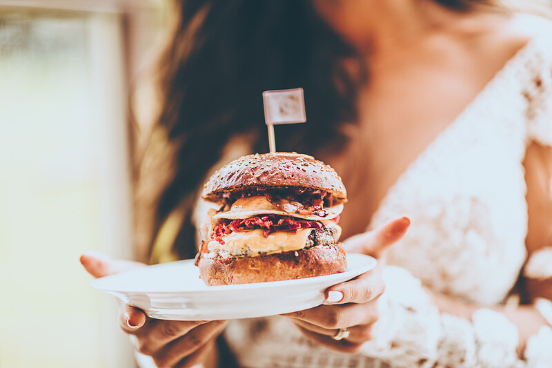 nevesta s burgerom, burger s vlajočkou, slnečné svetlo na svadobnej hostine, radostná nálada pri jedle, nevesta v bielych šatách, burger na tanieri. Golf Club Welten, Báč.