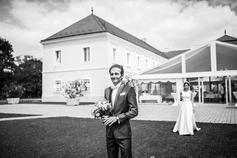čiernobiely záber prvého stretnutia na trávniku, ženích s kyticou, nevesta prichádza spoza neho. Art Hotel Kaštieľ Tomášov.