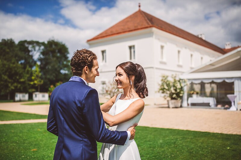 novomanželia v objatí na trávniku pred kaštieľom, svadobný stan a zeleň v pozadí. Art Hotel Kaštieľ Tomášov.