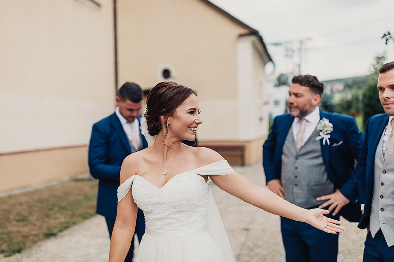 nevesta v bielych šatách, ženích v modrom obleku, svadobný sprievod, vonkajšia slávnosť, denné svetlo, radosť a smiech. Kaštieľ Villa Bork, Borčice.