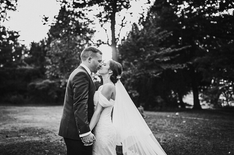 nevesta a ženích sa bozkávajú, pár držiaci sa za ruky, slnečný deň medzi stromami, romantický moment pod stromom, svadobný pár v prírode. Kaštieľ Villa Bork, Borčice.