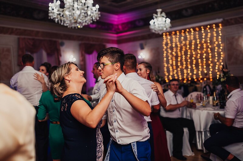 hostia tancujú vo dvojiciach, svetelný záves a lustre nad parketom. Hotel Jeleň, Hlohovec.