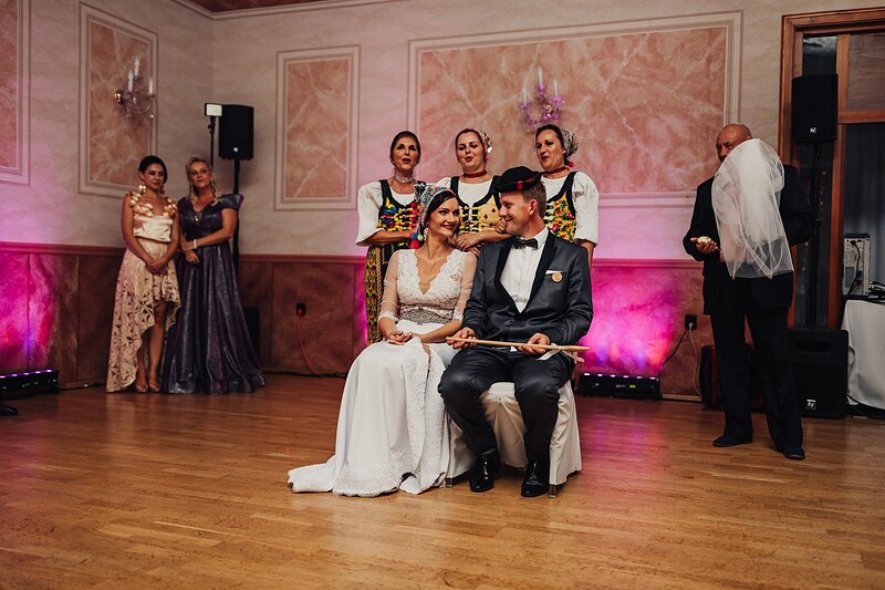 novomanželia sedia uprostred sály počas čepčenia, ženích v klobúku, muž so závojom v rukách. Hotel Jeleň, Hlohovec.
