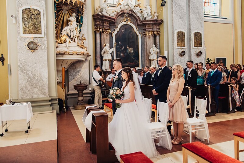 pohľad do barokového kostola počas obradu, hlavný oltár a hostia v laviciach. Kaštieľ Klobušice.