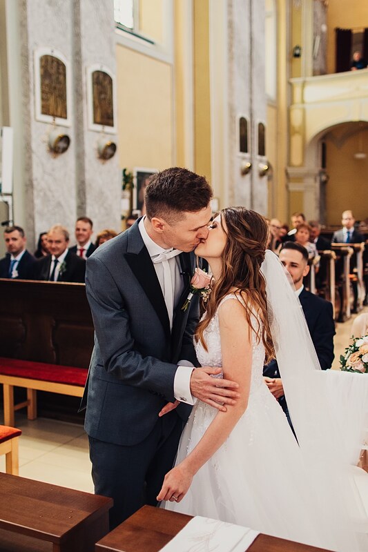 prvý bozk v kostole, ženích objíma nevestu, svedkovia a hostia v pozadí. Kaštieľ Klobušice.