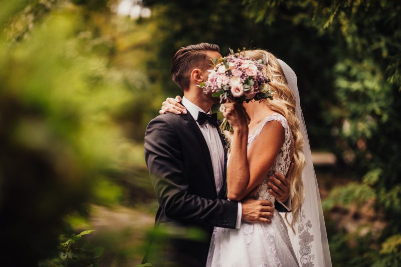 nevesta s kvetmi, ženích a nevesta v záhrade, svadobný pár v prírode, nevesta vo vlečke, slnečné svetlo v záhrade, romantický moment v zeleňi. Hotel Zlatý Kľúčik, Nitra.