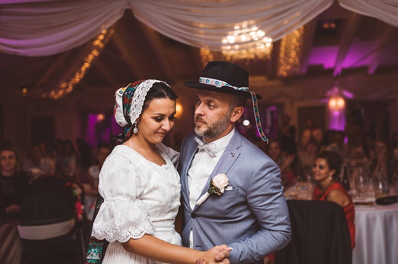 nevesta v čepci a bielej krojovej blúzke tancuje so ženíchom, ženích v klobúku s farebnou stuhou, hostia pri stoloch. Hotel Zlatý Kľúčik, Nitra.