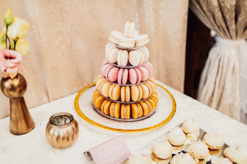 makrónky na svadobnom stole, zlatá dekorácia a kvety, elegantná sála s béžovými záclonami, pyramída makróniek v pastelových farbách, slávnostný stôl s dekoráciami. Pálenica Jelšovce.