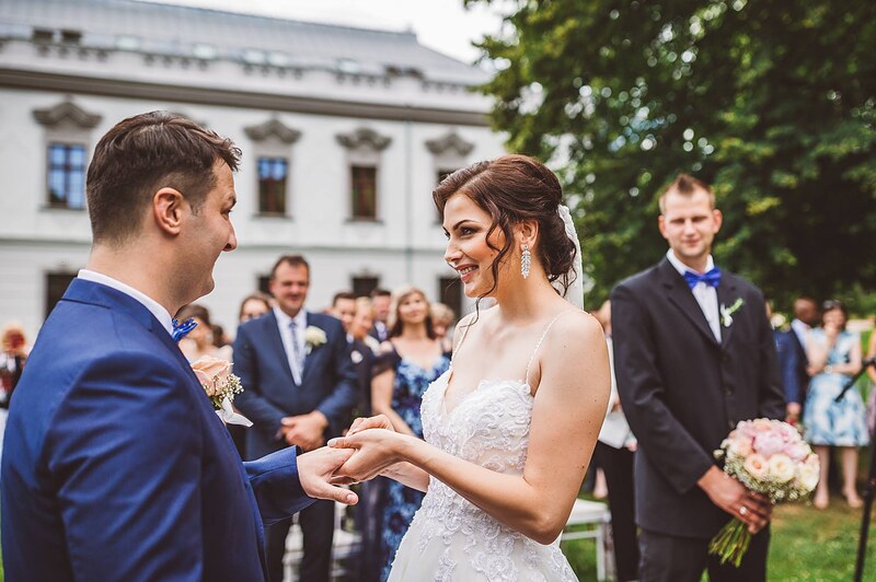 výmena obrúčok počas obradu vonku, ženích navlieka neveste prsteň, svedkovia po stranách. Kaštieľ Orlové, Považská Bystrica.