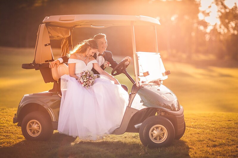pár v golfovom vozíku pri západe slnka, nevesta s kyticou na kolenách, ženích za volantom. Penati Golf Resort, Senica.