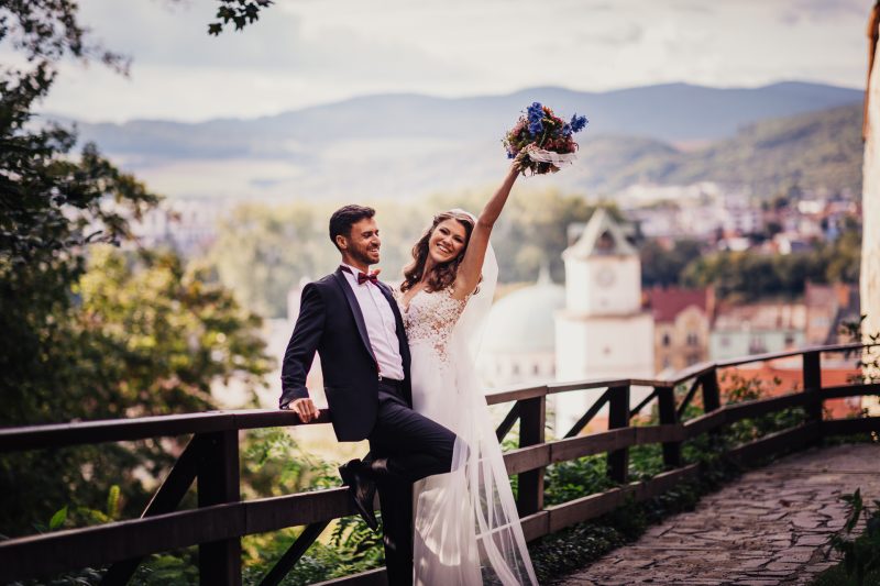 nevesta s kvetmi, ženích a nevesta na balkóne, horský výhľad, biele svadobné šaty, pár s výhľadom na údolie, slnečný deň v horách. Fatima, Trenčín.