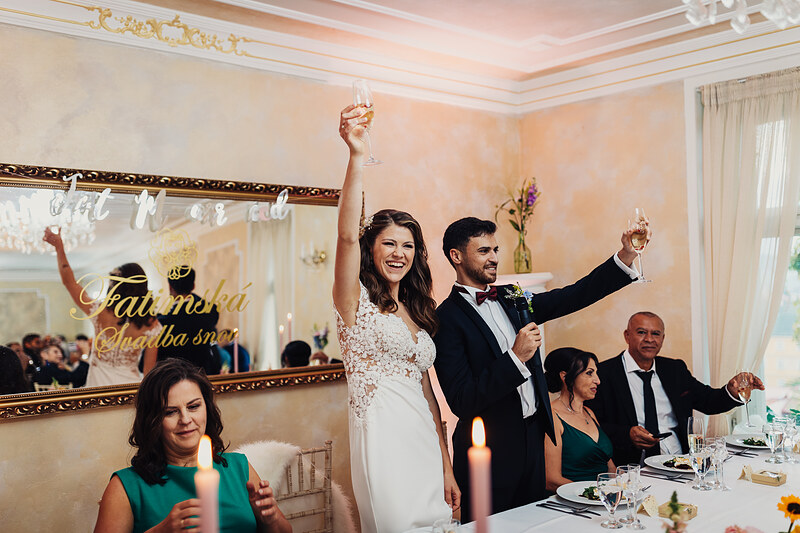 nevesta s pohárom, ženích s mikrofónom, svadobný prípitok, elegantná jedáleň, sviečky na stole, zlaté zrkadlo. Fatima, Trenčín.