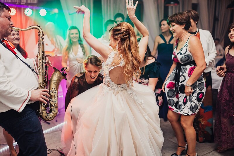 saxofonista hrá priamo na parkete, nevesta tancuje so zdvihnutými rukami, hostia okolo. Gazdovstvo Uhliská.