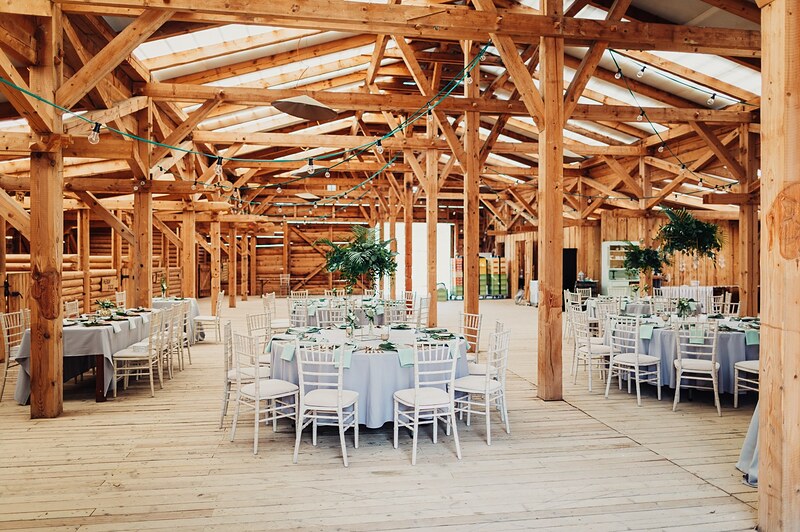 pohľad do stodoly z výšky, okrúhle stoly s bielymi stoličkami pod masívnym dreveným krovom. Ranch 13, Nemšová.