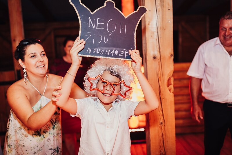 chlapec v parochni a hviezdicových okuliaroch drží tabuľu s nápisom Nech žijú novomanželia. Ranch 13, Nemšová.