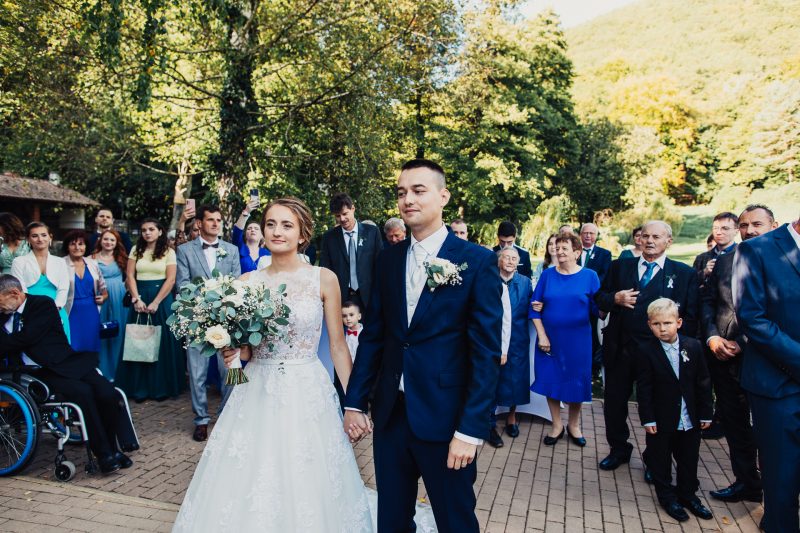 novomanželia prichádzajú medzi hostí, potlesk a úsmevy, zalesnený kopec nad areálom. Vila Sokolka, Trenčín.