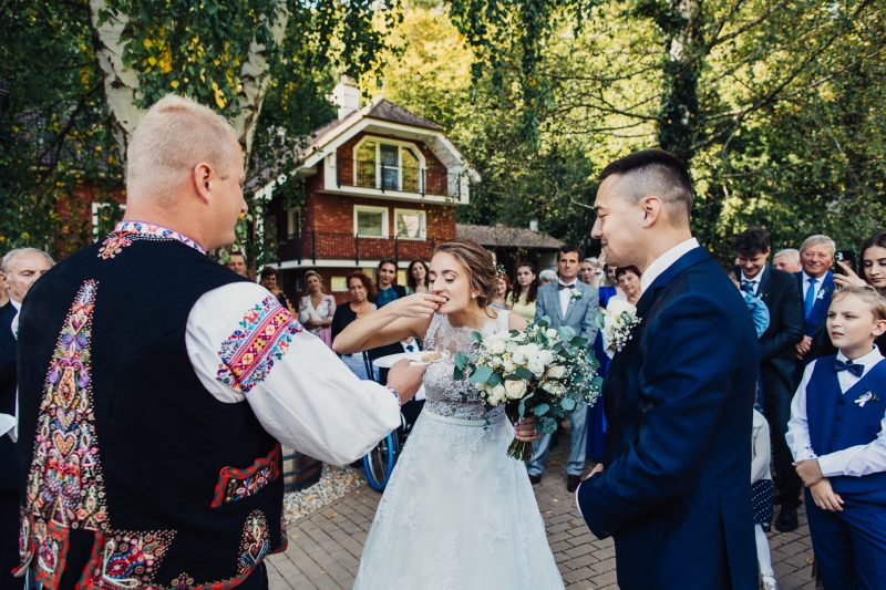 nevesta ochutnáva chlieb so soľou, ženích sa na ňu pozerá, hostia a deti okolo v polkruhu. Vila Sokolka, Trenčín.