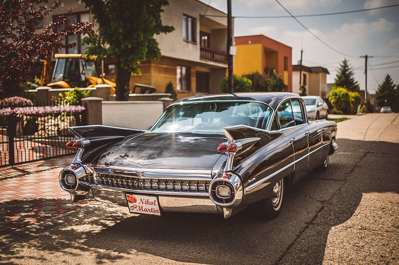 historický Cadillac s chrómovanými plutvami zaparkovaný pred domom, tabuľka s menami novomanželov. Holiday Inn Trnava.
