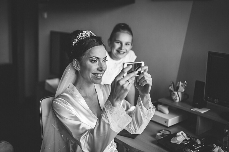 čiernobiely záber, nevesta s dievčatkom si prezerajú fotku v mobile počas príprav. Holiday Inn Trnava.