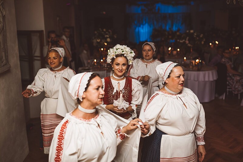 ženy v krojoch prichádzajú do sály, nevesta s kvetinovou čelenkou medzi nimi, začiatok čepčenia. Kaštieľ Krasňany, Žilina.