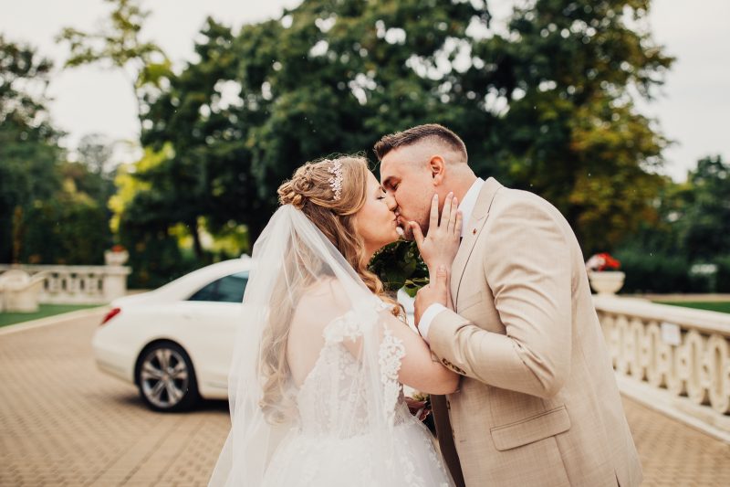 nevesta a ženích sa bozkávajú, svadobný pár v parku, nevesta vo svadobných šatách, ženích v béžovom obleku, prvý bozk, slnečný deň v prírode. Art Hotel Kaštieľ Tomášov.