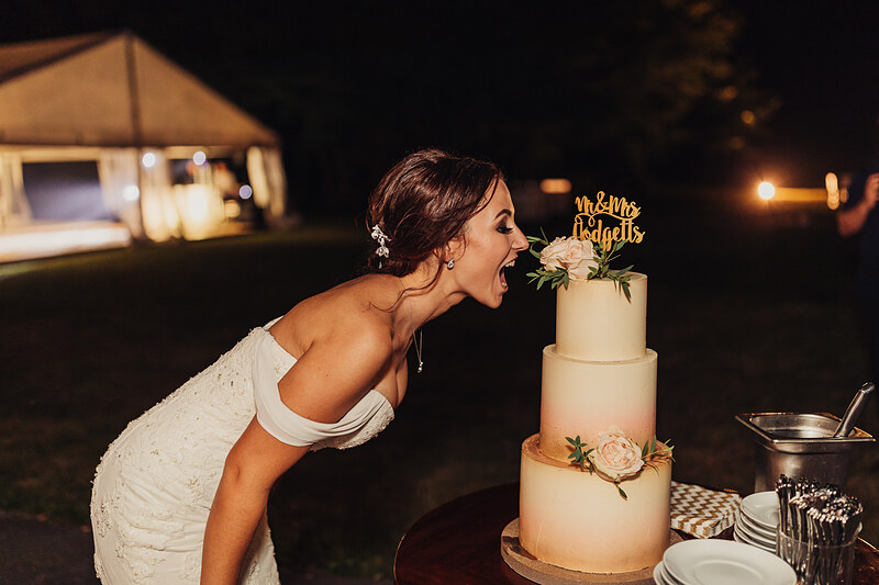 nevesta pri torte v noci, trojposchodová svadobná torta, osvetlený stan v pozadí, nevesta ochutnáva tortu, nočná svadobná oslava, teplé svetlo v tme. Kaštieľ Villa Bork, Borčice.